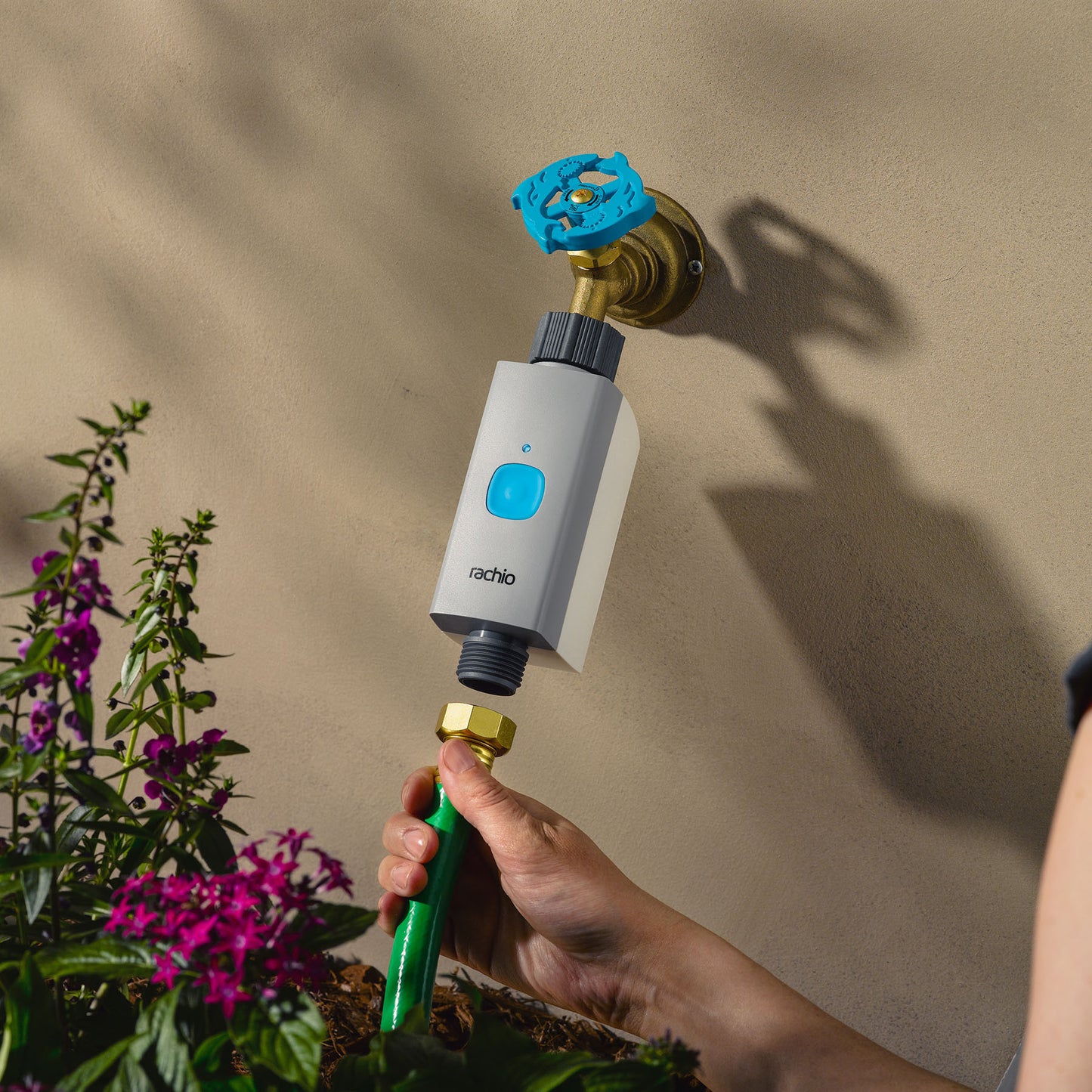Woman attaching hose to Rachio Smart Hose Timer valve on outdoor spigot.