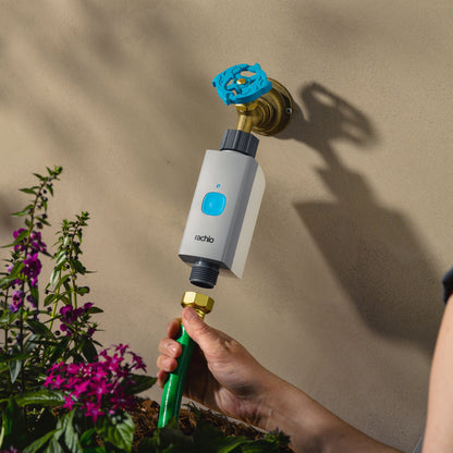 Woman attaching hose to Rachio Smart Hose Timer valve on outdoor spigot.