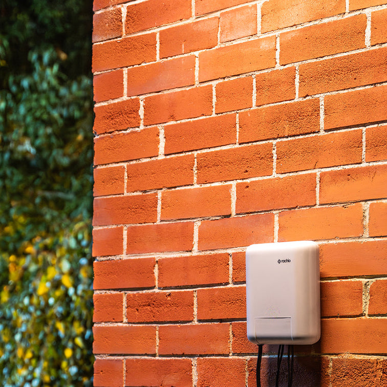 Smart Lighting Controller on a red brick wall with green foliage in the background